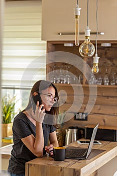 Woman having phone conversation while working remotely from home