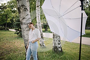 Woman having photo session in nature while leaning against birch tree