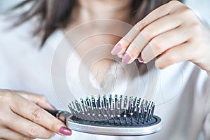 Woman having problem with hair loss hand holding hair fall on comb