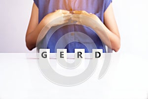 Woman having a reflux acid with the word gerd on wood block,Gastroesophageal reflux disease