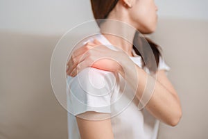 Woman having Shoulder and Neck pain during sitting on couch at home. Muscle painful due to Myofascial pain syndrome and