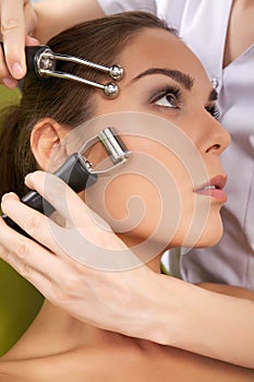 Woman having a stimulating facial treatment from a therapist