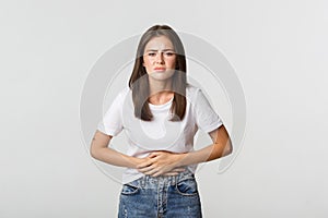 Woman having stomach ache, bending and holding hands on belly, discomfort from menstrual cramps. Girl feeling nauseous