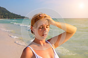 Woman having sun stroke on sunny beach. Woman on hot beach with sunstroke.