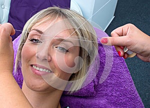 Woman having threading hair removal procedure