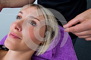 Woman having threading hair removal procedure