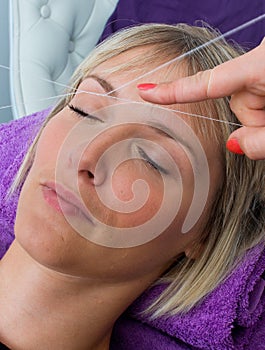 Woman having threading hair removal procedure