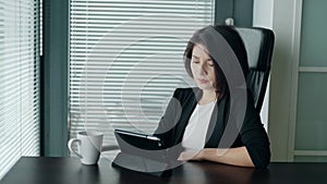 Woman having troubles with work or app crash. Young business lady sitting behind the desk with tablet, shaking head