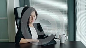 Woman having troubles with work or app crash. Young business lady sitting behind the desk with tablet, shaking head