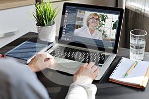 Woman having video conference with colleagues at table. Multiethnic business team working from home using laptop