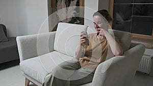 Woman having videocall on smartphone. girl making chat online on phone at home