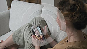 Woman having videocall on smartphone. girl making chat online on phone at home