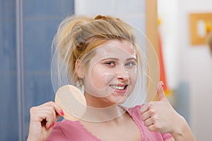 Woman having wash gel on face holding sponge