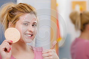 Woman having wash gel on face holding sponge