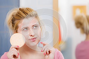 Woman having wash gel on face holding sponge