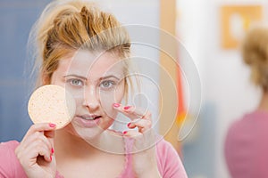 Woman having wash gel on face holding sponge