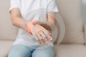 Woman having wrist pain during sitting on sofa at home, muscle ache due to De Quervain s tenosynovitis, ergonomic, Carpal Tunnel