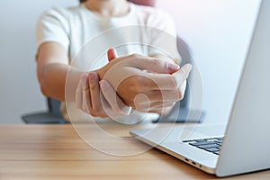 Woman having wrist pain when using laptop computer and mouse during working long time on workplace. De Quervain s tenosynovitis,