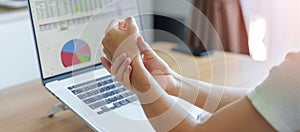 Woman having wrist pain when using laptop computer and mouse during working long time on workplace. De Quervain s tenosynovitis,
