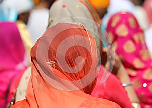 woman with head covered by a colorful orange veil during an outd