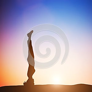 Woman in head stand yoga pose meditating at sunset. Zen