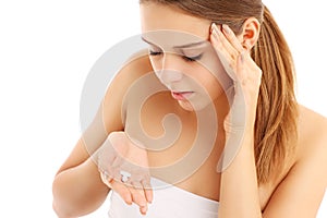 Woman with headache holding pain killers