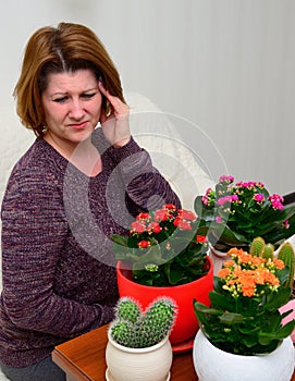 Woman with a headache near the pot plants