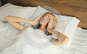 Woman with headache, pain tension in head, suffers from migraine lying in bed