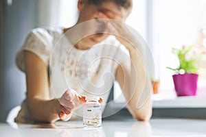 Woman with headache reaching for painkiller pills. migraine, cephalalgia and stress concept