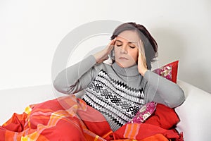 Woman with a headache sitting on the couch