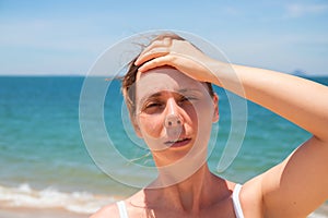 Woman with headache on sunny beach. Young woman having sunstroke. Health problem on vacation. Medicine on vacation