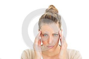 Woman with headache touching her temples looking at camera