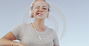 Woman, headphones and blow bubble with gum, smile and wink face with listening to music by sky background. Gen z girl