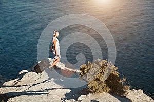 Woman in headphones holding laptop and suitcase. Seascape on background. Business travelling and dream job concept