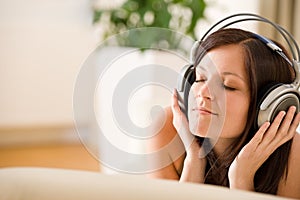 Woman with headphones listen to music in lounge