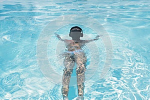 Woman in the headphones listening to the  music bathing in a pool