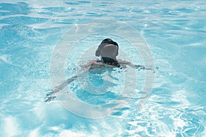 Woman in the headphones listening to the  music bathing in a pool