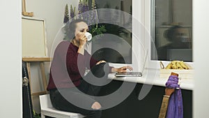 Woman in headphones listening to music and working from home at remote workplace during pandemic. Young female student studying on