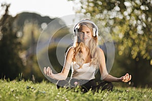 Woman in headphones meditating at green park