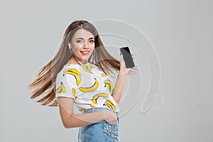 Woman with headphones showing blank smartphone screen