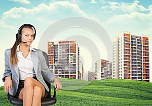 Woman in headphones sits on chair. Buildings