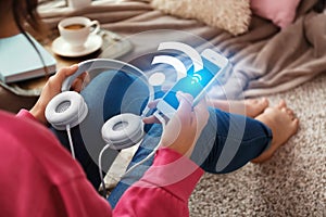 Woman with headphones and smartphone using free Wi-Fi at home