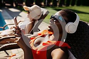 Woman in headphones sunbathing on sun bed at pool