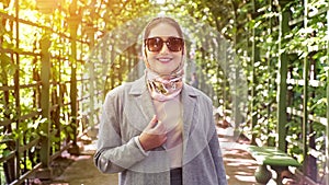 woman in headscarf and sunglasses smiling in garden arch