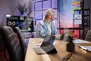 Woman in headset sitting at desk and typing on laptop