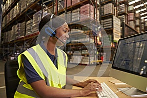 Woman with headset working in on-site office of a warehouse