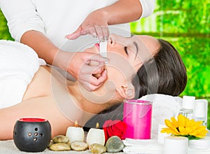 Woman headshot profile, lying with eyes closed and hand applying wax paper to upper lip of client