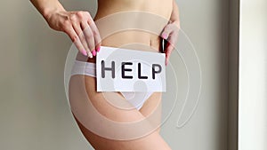 Woman Health Problem. Closeup Of Female With Fit Slim Body In Panties Holding White Card With Word Help Near Her Stomach