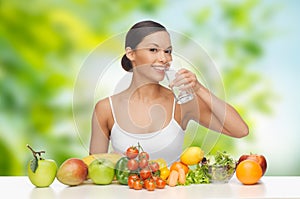 Woman with healthy food on table drinking water