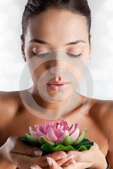 A woman with healthy hydrated skin holds a lotus flower spa and skincare concept